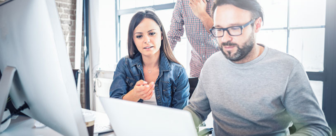 Employees working together around a laptop