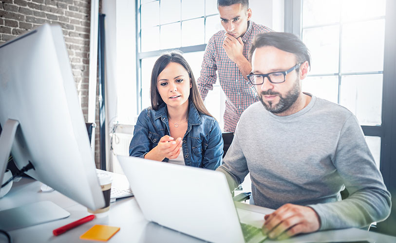 Employees working together around a laptop