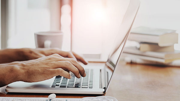 Detail of person's hands working at their laptop