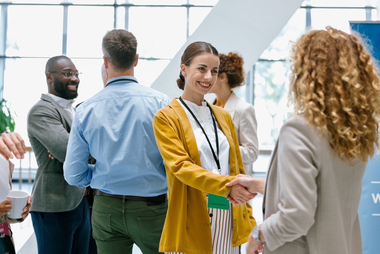 Confident businesswomen handshaking while in the corridor in front of the conference hall