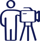 Dark blue line icon of a person standing behind a video camera on a tripod.